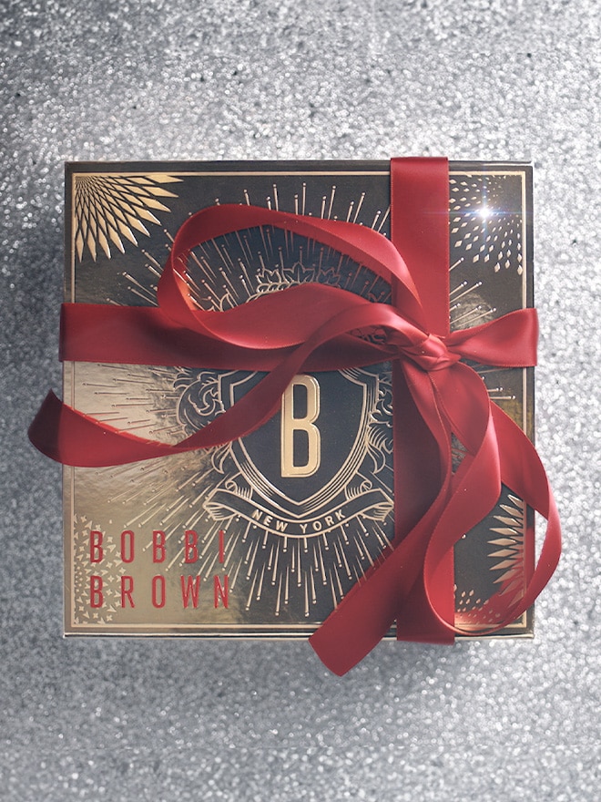 Bobbi Brown gift boxes animating in a stacking formation, in front of a gold, deco style background